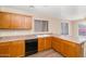 This is a well-lit kitchen with wood cabinets, a black dishwasher, and a view of the greenery outside at 12450 W Hearn Rd, El Mirage, AZ 85335