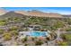 Aerial view of the community pool, lounge chairs, umbrellas, and desert landscape and mountain backdrop at 15037 N 114Th Way, Scottsdale, AZ 85255