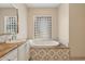 Relaxing soaking tub with patterned tile surround and glass block window providing natural light at 15037 N 114Th Way, Scottsdale, AZ 85255