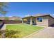 This lovely backyard has artificial grass, a covered patio, brick walls, and mountain views in the distance at 16551 W Desert Ln, Goodyear, AZ 85338