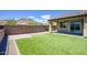 Inviting backyard featuring artificial grass, desert landscaping, covered patio, and desert views at 16551 W Desert Ln, Goodyear, AZ 85338