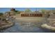 Scenic community entrance with stacked stone monument, lush landscaping, and a tranquil water feature at 16551 W Desert Ln, Goodyear, AZ 85338