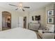 Well lit primary bedroom with an elegant chair, television, and access to the primary bath at 1776 E Laddoos Ave, Queen Creek, AZ 85140