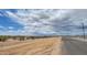 Newly paved street in a growing neighborhood with desert landscaping in the right-of-way with storm clouds at 18224 W La Senda Dr, Surprise, AZ 85387