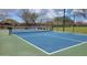 Well-maintained community tennis court with a blue surface, surrounded by a chain-link fence and manicured landscaping at 18224 W La Senda Dr, Surprise, AZ 85387