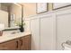 This bathroom features wainscotting, a wooden vanity with a white sink, and modern fixtures at 18419 W Maui Ln, Surprise, AZ 85388