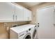 Well-lit laundry room featuring modern washer and dryer appliances with overhead cabinets at 20608 N 57Th Ave, Glendale, AZ 85308
