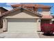 Tan two-story home featuring a two-car garage and vibrant red bougainvillea bush at 22320 W Morning Glory St, Buckeye, AZ 85326