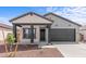 Charming single-story home featuring a covered porch, dark-colored accents, and desert-friendly landscaping at 23385 W Burton Ave, Buckeye, AZ 85326