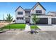 Beautiful two-story home boasts white brick, dark accents, artificial turf, and a spacious driveway leading to garages at 26619 S 169Th Pl, Queen Creek, AZ 85142
