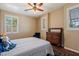 Cozy bedroom featuring white plantation shutters, antique dresser, a ceiling fan, and a comfortable bed with patterned bedding at 3350 S Holguin Way, Chandler, AZ 85248