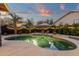 This backyard includes a freeform pool, lush landscaping and desert landscaping with an umbrella and lounge chairs at 3842 W Ironwood Dr, Chandler, AZ 85226