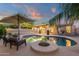 This backyard includes a pool, umbrella, palm tree, chairs and string lights for nighttime ambience at 3842 W Ironwood Dr, Chandler, AZ 85226
