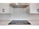 Elegant kitchen with a smooth cooktop, tiled backsplash, stainless steel range hood, and custom white cabinetry at 3989 E Freeman Ln, San Tan Valley, AZ 85140