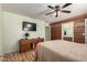 Comfortable bedroom with a ceiling fan, TV, wood accent wall, and adjoining bathroom at 40264 W Lococo St, Maricopa, AZ 85138