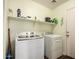 Bright laundry room with modern washer and dryer units and open shelving above at 40264 W Lococo St, Maricopa, AZ 85138