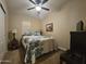Cozy bedroom with ceiling fan, floral comforter, side table, and a dark dresser at 650 N Hawes Rd # 4007, Mesa, AZ 85207