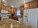 A kitchen with wood cabinets, granite counters and a white refrigerator and appliances at 650 N Hawes Rd # 4007, Mesa, AZ 85207