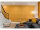 Cozy living room featuring textured gold wall, gray sectional, and stairs with black metal railing at 6957 E Osborn Rd # A, Scottsdale, AZ 85251