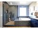 Modern bathroom featuring a soaking tub and a glass-enclosed walk-in shower with dark subway tile at 7512 W Warner St, Phoenix, AZ 85043