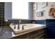 The soaking tub offers a relaxing spot below a bright window and beside custom tile work and cabinets at 7512 W Warner St, Phoenix, AZ 85043