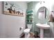 Cozy powder room featuring pedestal sink, toilet, and decorative shelving at 7512 W Warner St, Phoenix, AZ 85043