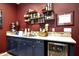 Entertainment room wet bar with stylish blue cabinets, wine fridge, and decorative shelves at 7512 W Warner St, Phoenix, AZ 85043