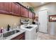 Well-organized laundry room with sink, front-loading washer/dryer, ample storage, and stylish decor at 8024 W Vista Ave, Glendale, AZ 85303