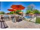 Backyard featuring a pool, outdoor kitchen, and lounge chairs under vibrant orange umbrellas at 8024 W Vista Ave, Glendale, AZ 85303