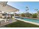 A refreshing backyard oasis with a pool, covered patio, outdoor kitchen, cactus landscaping, and palm trees at 8730 E Montecito Ave, Scottsdale, AZ 85251