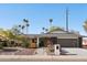 Charming single-story home with desert landscaping, palm trees, and a modern dark gray two-car garage at 8730 E Montecito Ave, Scottsdale, AZ 85251