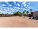 Spacious gravel backyard with storage sheds, windmill, and palm trees at 930 E Friar Ave, Apache Junction, AZ 85119