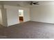 Spacious bedroom featuring neutral carpet, ceiling fan, and an open doorway leading to an ensuite bathroom at 9556 W Blue Sky Dr, Peoria, AZ 85383
