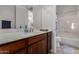 Bathroom featuring a wooden vanity, white countertops, a large mirror, and a shower-tub combo with a blue shower curtain at 10040 E Grandview St, Mesa, AZ 85207