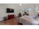 Bright main bedroom featuring wood floors, TV, windows with outdoor views, and seating area at 10040 E Grandview St, Mesa, AZ 85207