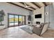 Spacious living room with stone floors, beamed ceiling, and a fireplace, opening to an outdoor pool area at 11123 E Monument Dr, Scottsdale, AZ 85262
