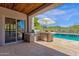 A beautiful outdoor kitchen area provides a built-in grill, counter space, and easy access to the pool in this backyard oasis at 11123 E Monument Dr, Scottsdale, AZ 85262