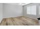 An empty bedroom features wood-look floors, a ceiling fan, and a large window with blinds at 12443 W Via Camille --, El Mirage, AZ 85335