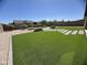 Spacious backyard with lush artificial turf, mature trees, and modern stepping stones at 12547 W Stella Ln, Litchfield Park, AZ 85340