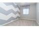 A carpeted bedroom featuring a window with valance and a gray and white zigzag accent wall at 12547 W Stella Ln, Litchfield Park, AZ 85340