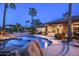 Backyard oasis with a pool, waterfall, and lush landscaping illuminated at twilight at 12820 N 83Rd Pl, Scottsdale, AZ 85260