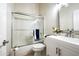 Clean bathroom featuring a shower-tub combo with glass doors, a toilet, and a vanity with a decorative mirror at 12820 N 83Rd Pl, Scottsdale, AZ 85260