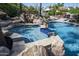 In-ground hot tub featuring stone and tile design with waterfall feature flowing into a blue swimming pool at 12820 N 83Rd Pl, Scottsdale, AZ 85260