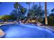 Backyard pool at night showcasing a unique waterfall feature and tropical landscaping at 12820 N 83Rd Pl, Scottsdale, AZ 85260