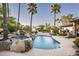 Stunning backyard pool with rock waterfall, mature landscaping, and ample seating for relaxation and entertainment at 12820 N 83Rd Pl, Scottsdale, AZ 85260
