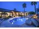 Beautiful backyard at dusk featuring a stunning pool, rock waterfall, and manicured landscaping at 12820 N 83Rd Pl, Scottsdale, AZ 85260