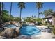 Stunning swimming pool featuring waterfalls and rocks, surrounded by lush landscaping and palm trees at 12820 N 83Rd Pl, Scottsdale, AZ 85260