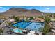 Aerial view of tennis courts, a community pool, palm trees, and residential homes against a mountain backdrop at 13007 N 1St St, Phoenix, AZ 85022