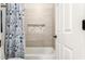 Tiled shower/tub with blue floral curtain adjacent to doorway at 13561 W Montebello Ave, Litchfield Park, AZ 85340