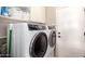 Bright laundry room featuring a white Electrolux washer/dryer, shelving and white cabinets for storage at 13561 W Montebello Ave, Litchfield Park, AZ 85340